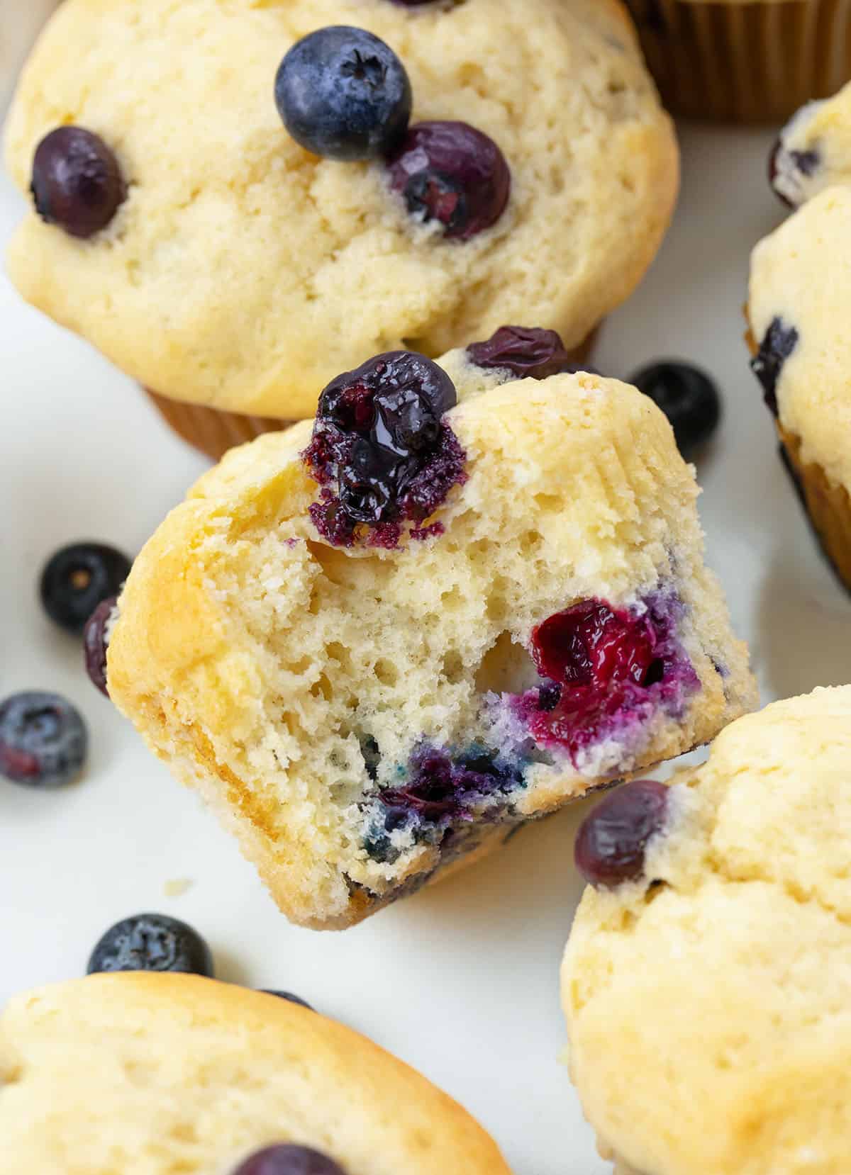 Close up of a halved Blueberry Buttermilk Muffin on a white table from overhead.