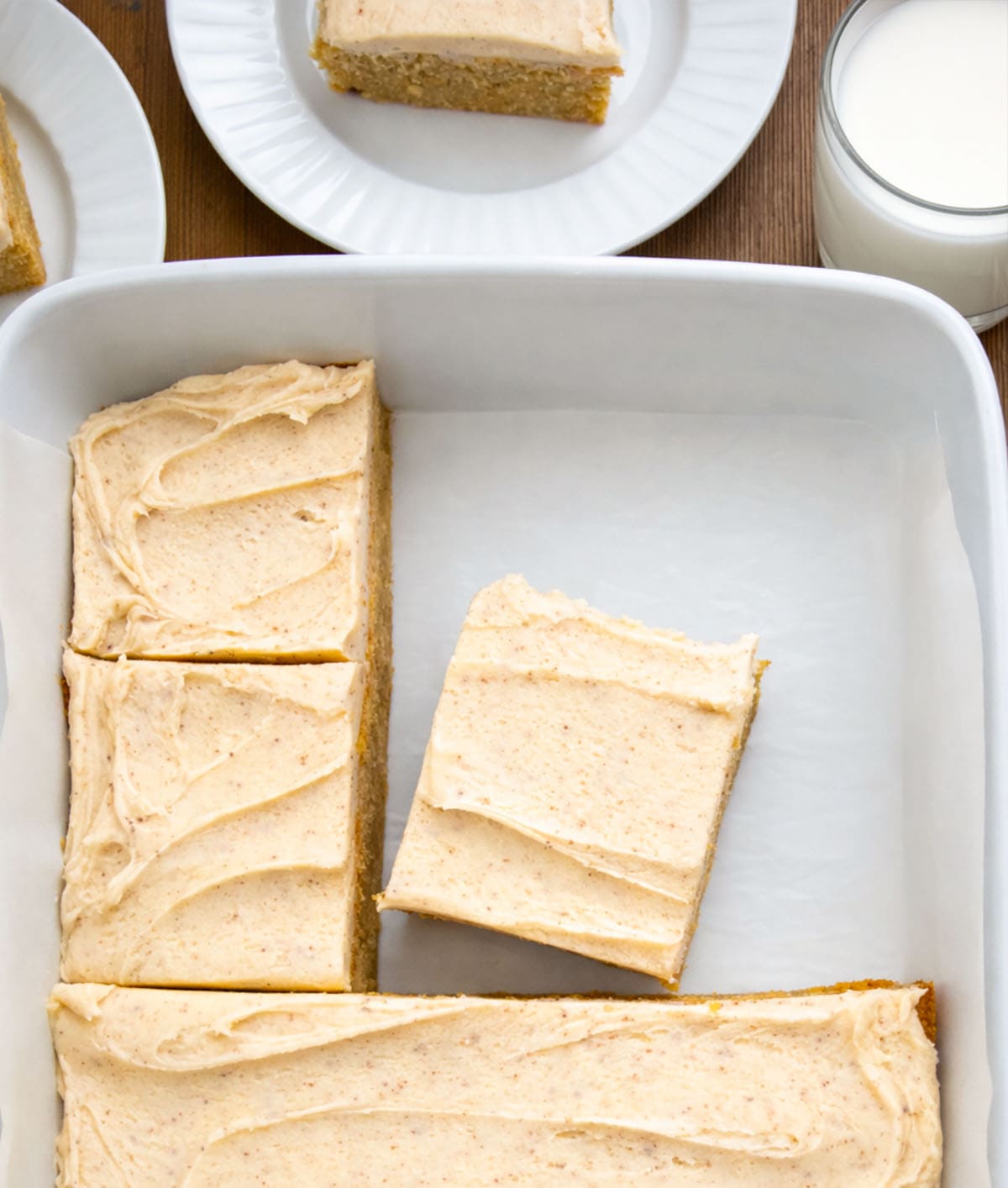 Cut up Browned Butter Banana Bars with Browned Butter Frosting in a white pan on a wooden table from overhead.