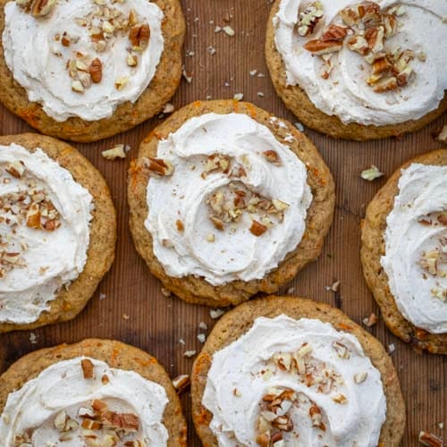 Carrot Cake Cookies frosted with brown sugar ermine on a wooden table from overhead.