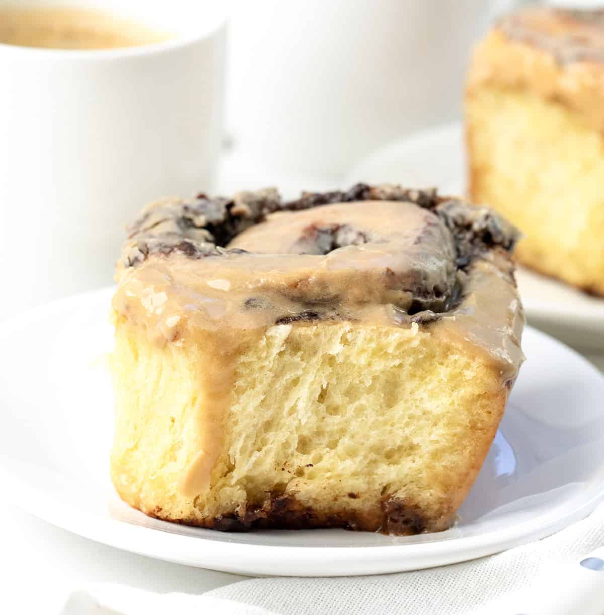 Chocolate Espresso Roll on a white plate on a white table with coffee mugs.