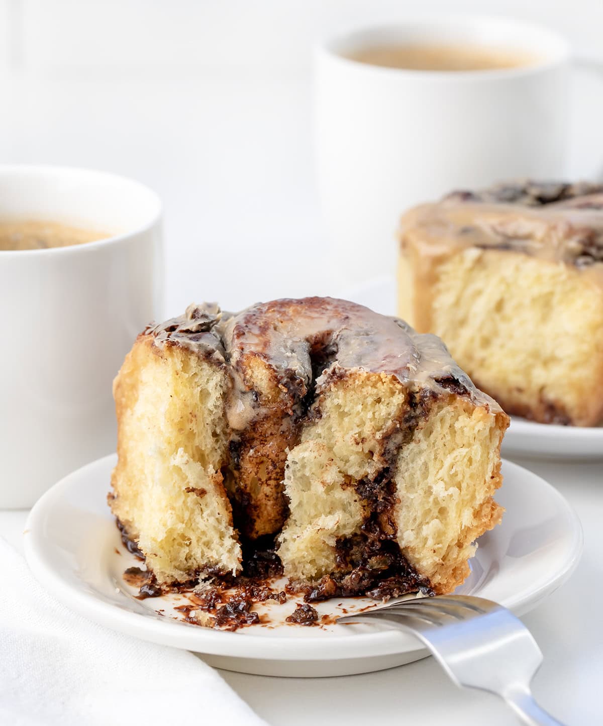 Cut into Chocolate Espresso Roll on a white plate with a fork resting on the plate.