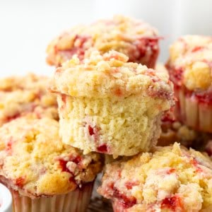 CLose up of unwrapped Double Strawberry Muffin on a pile of other muffins.