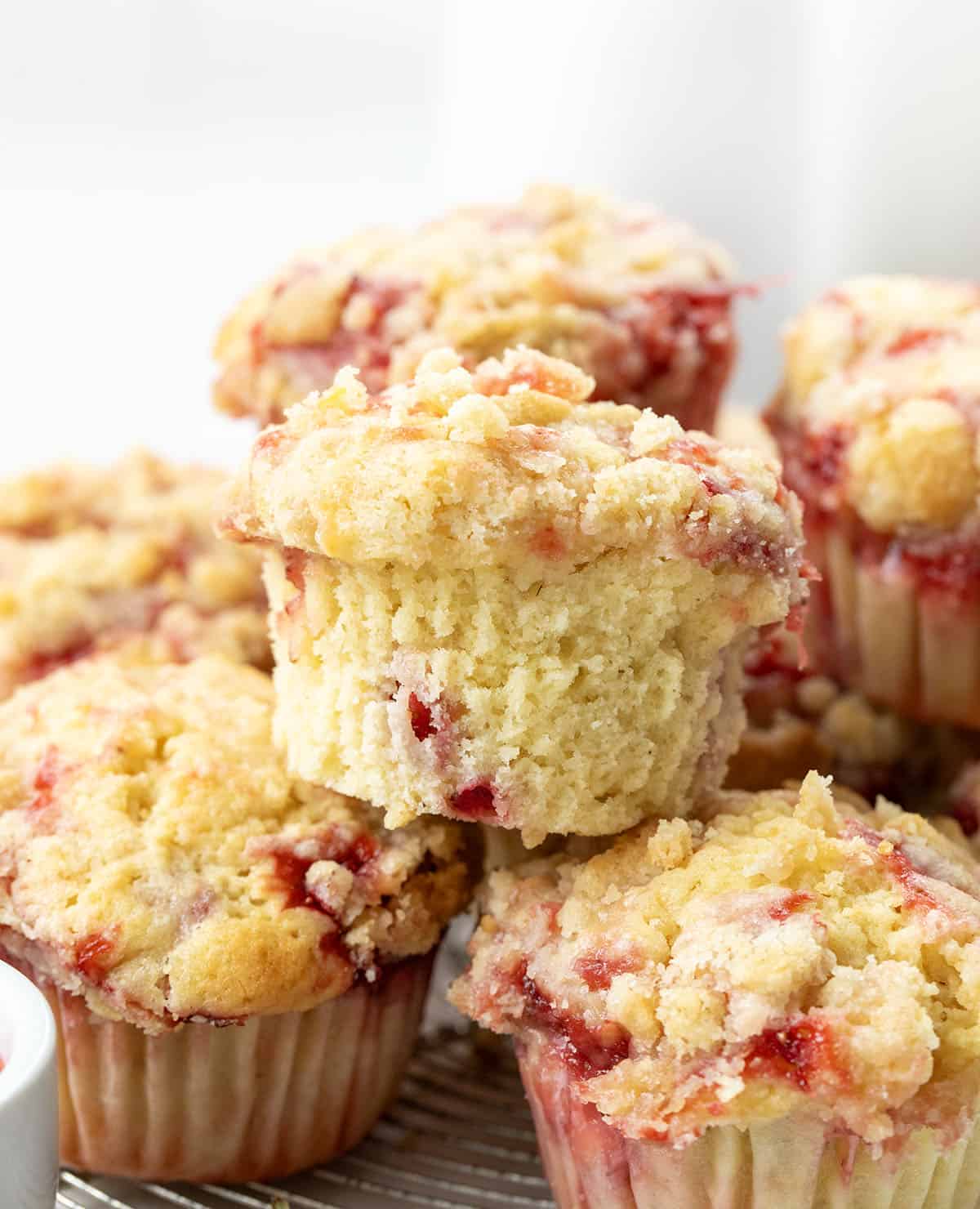 CLose up of unwrapped Double Strawberry Muffin on a pile of other muffins.