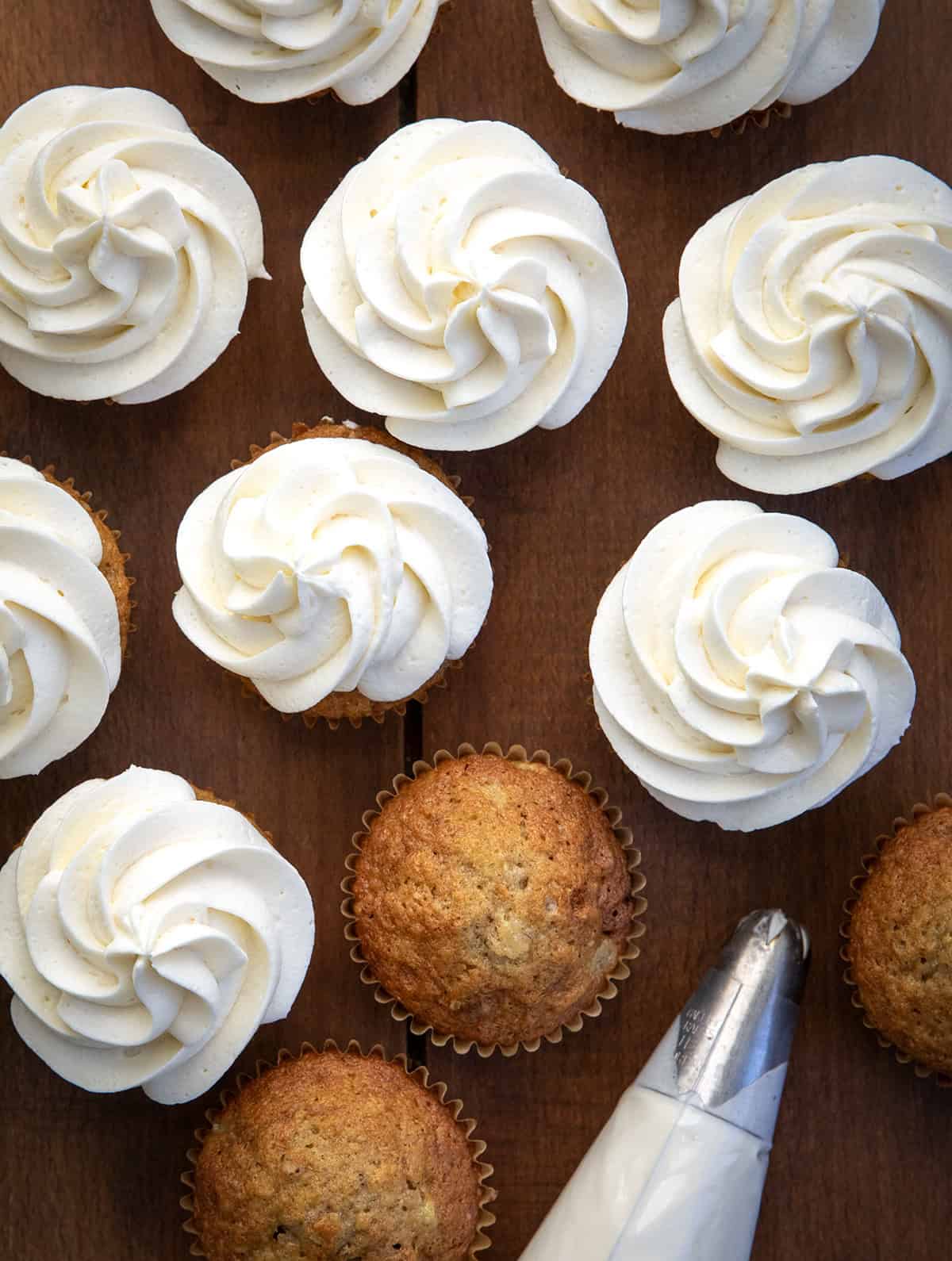 Hummingbird Cupcakes on a wooden table with a couple of cupcakes unfrosted.