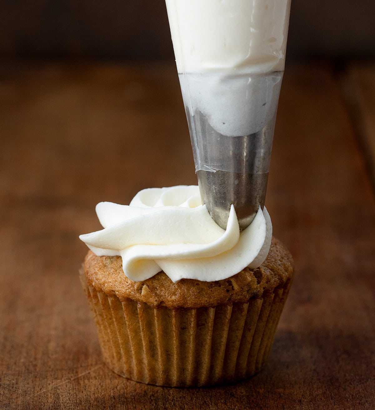 Piping frosting onto a Hummingbird Cupcake.