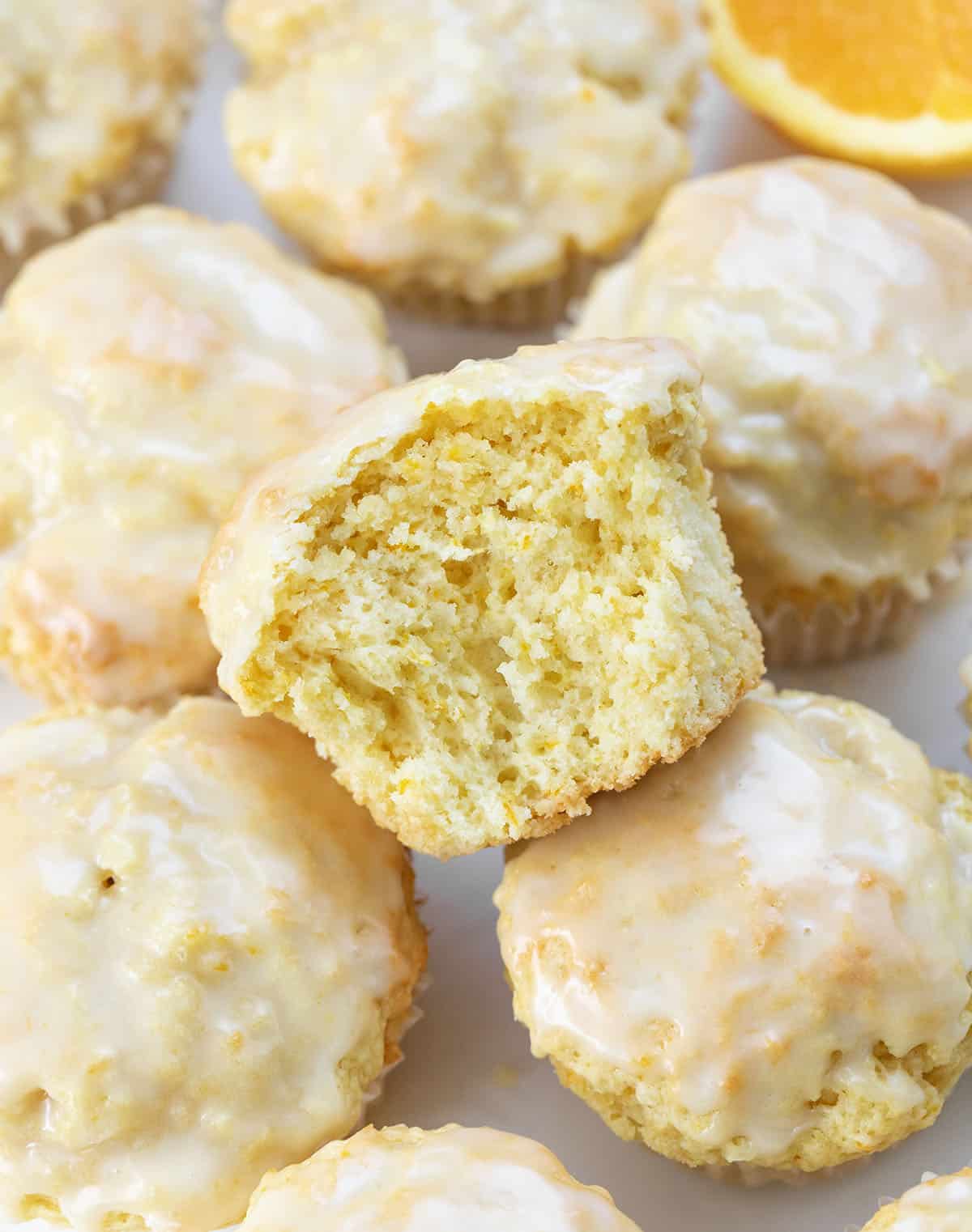 Bright, fluffy, and bursting with fresh orange flavor, these orange vanilla buttermilk muffins are a bakery-style treat you can make right at home. The combination of citrus zest, warm vanilla, and tender buttermilk crumb makes every bite soft, citrusy, and completely irresistible! Orange Vanilla Buttermilk Muffin halved sitting on top of other muffins.