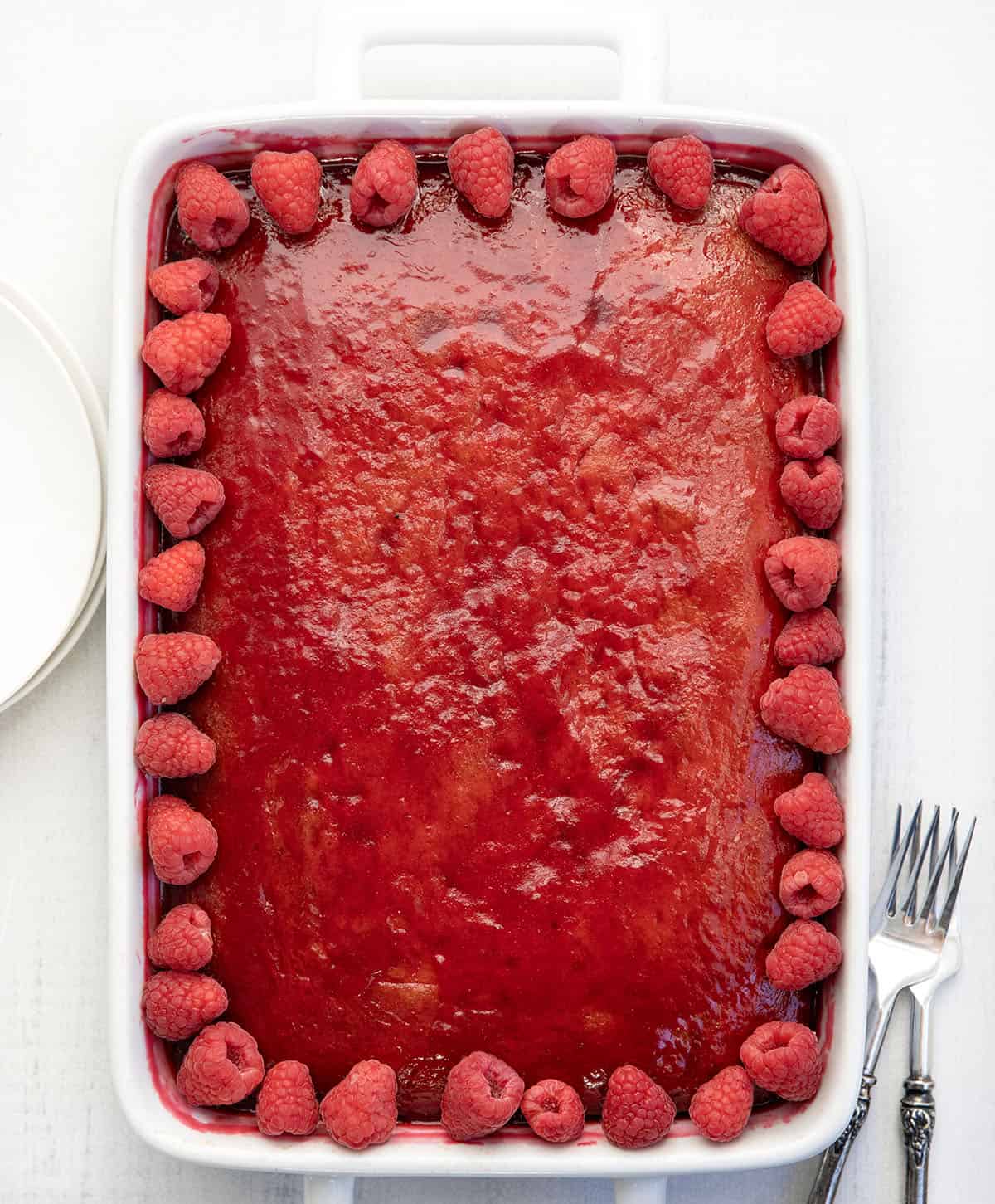 Whole Raspberry Sauce Cake in a white pan on a white table from overhead. 