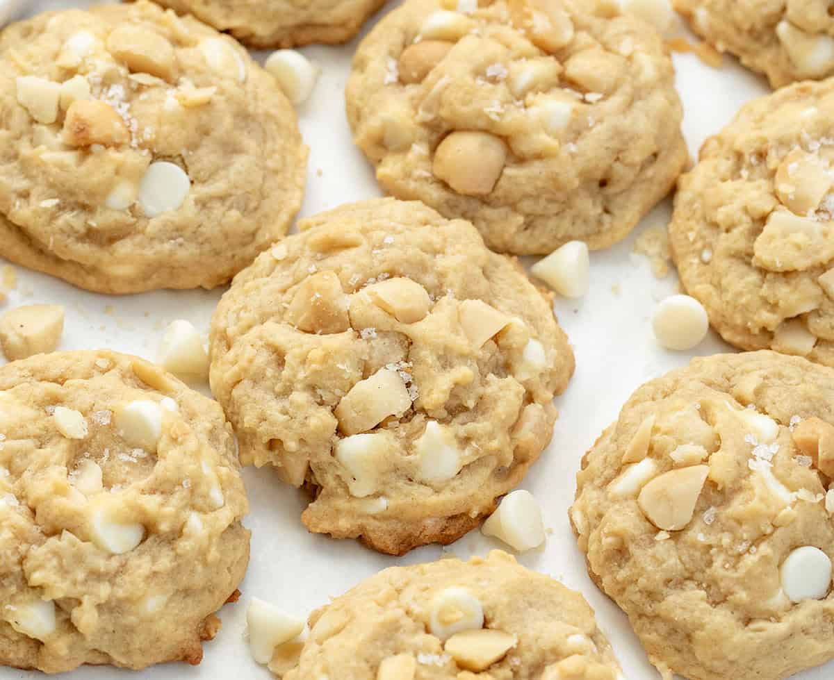 Golden, buttery, and packed with white chocolate and macadamia nuts! These Salted Honey White Chocolate Macadamia Nut Cookies are soft in the center, lightly crisp at the edges, and sprinkled with just the right touch of flaky sea salt! Salted Honey White Chocolate Macadamia Nut Cookies surrounded by more cookies and white chocolate chip morsels.