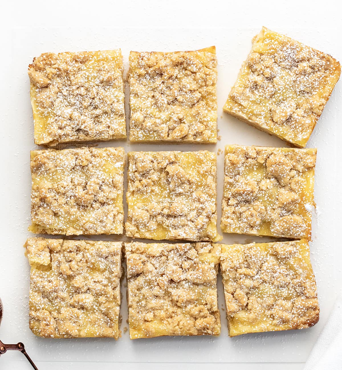 These Vanilla Cream Crumb Bars start with a buttery shortbread crust layered with a smooth vanilla custard filling, and are finished with a golden brown crumble topping! Vanilla Cream Crumb Bars cut into squares on a white table.