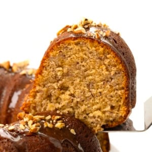 Picking up a piece of Banana Bundt Cake covered in brown sugar glaze and chopped nuts.