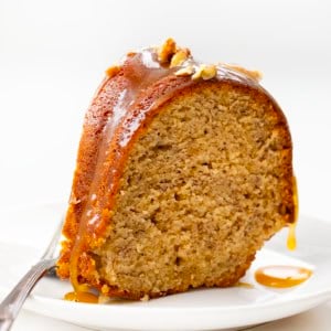Piece of Banana Bundt Cake on a white plate and dripping with brown sugar glaze.
