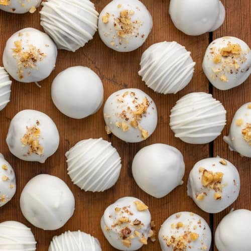 Carrot Cake Truffles with chopped nuts and chocolate drizzle on a wooden table from overhead.