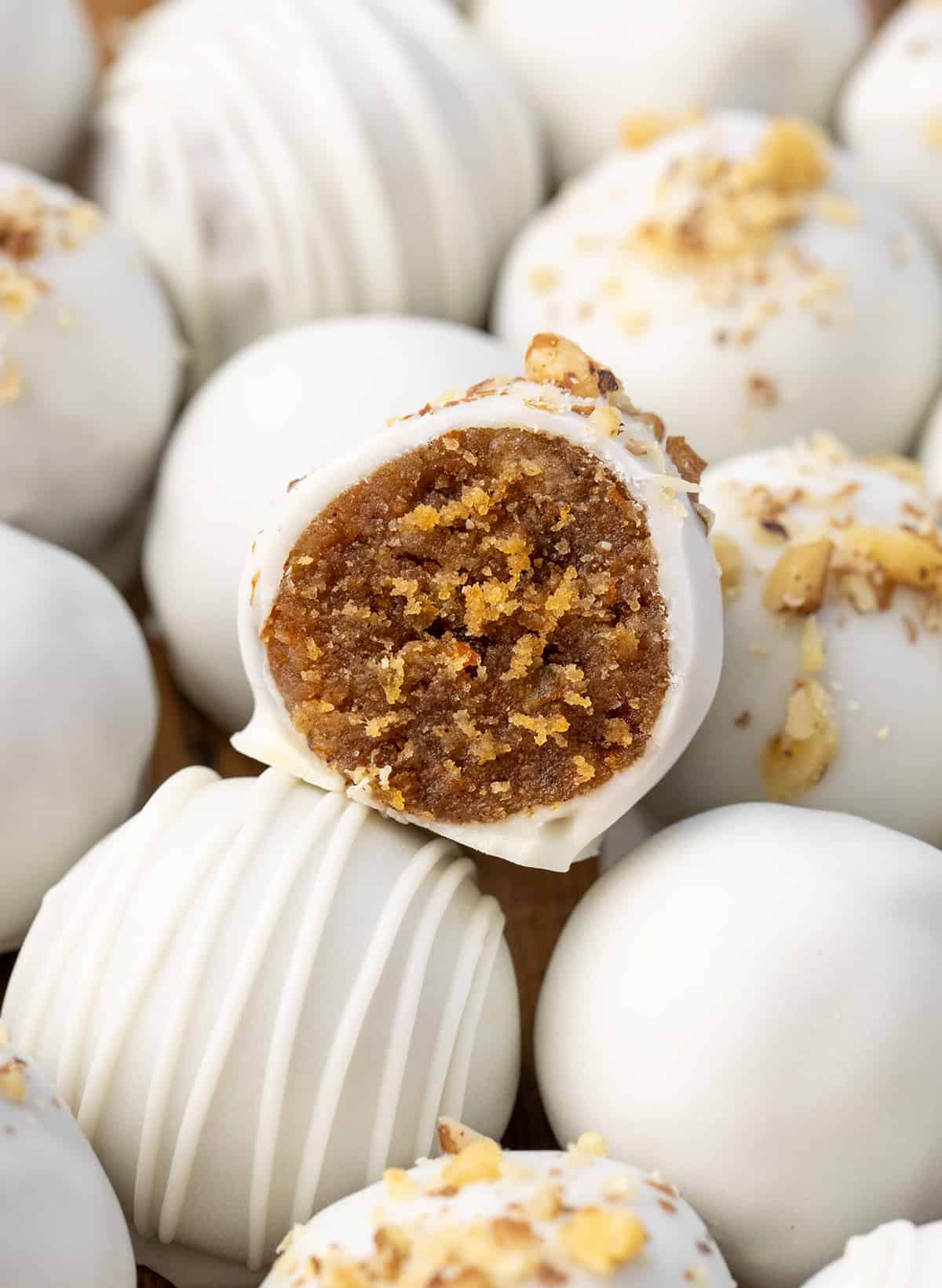 These Carrot Cake Truffles turn classic carrot cake into sweet, bite-sized treats! Made with homemade carrot cake, creamy frosting, and dipped in smooth vanilla bark, theyโre perfect for Easter, spring parties, or whenever youโre craving a little dessert. Close up of a cut in half Carrot Cake Truffle.