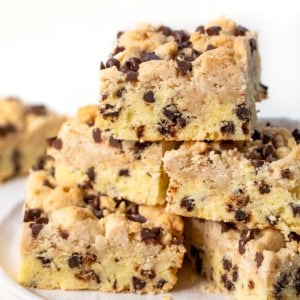 Chocolate Chip Crumb Cake stacked on a white plate on a white table.
