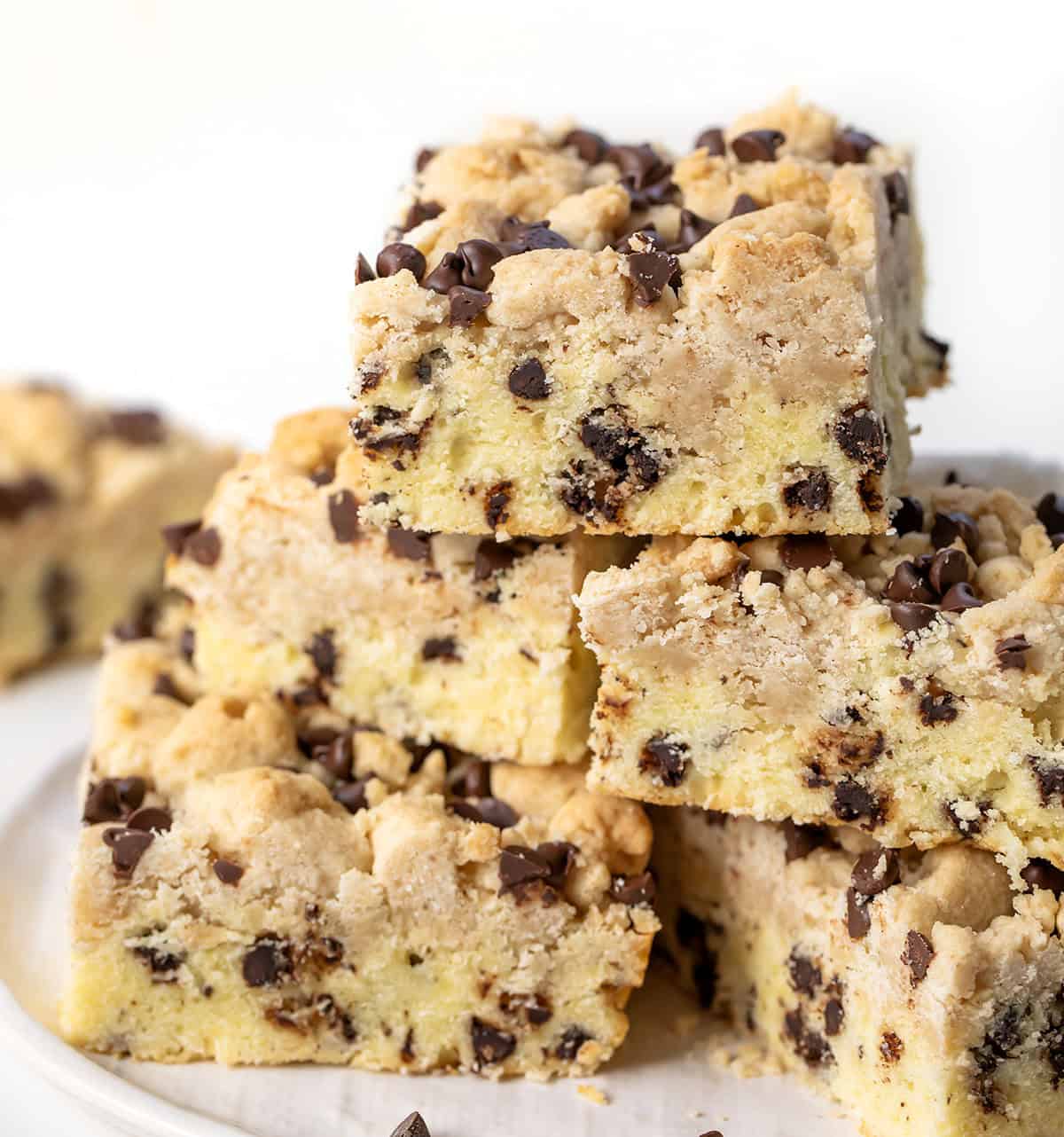 Chocolate Chip Crumb Cake stacked on a white plate on a white table.
