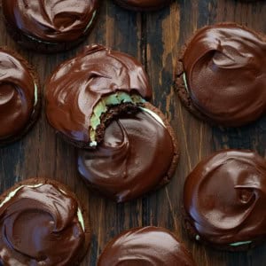 Chocolate Mint Cookies on a wooden table with one cookie bit into and resting on another cookie.
