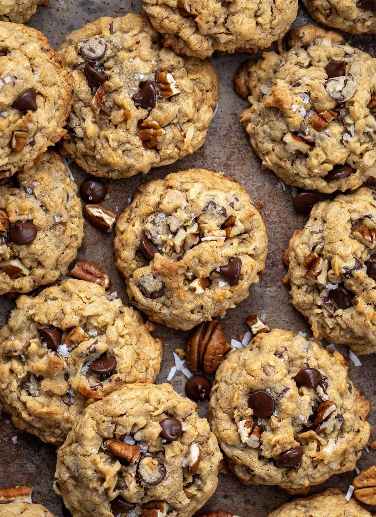 These Cowboy Cookies are thick, chewy, and loaded with oats, chocolate chips, pecans, and coconut. Each bite is soft in the middle with lightly golden edges and a little crunch from the nuts and coconut! Cowboy Cookies on a sheet pan from overhead.
