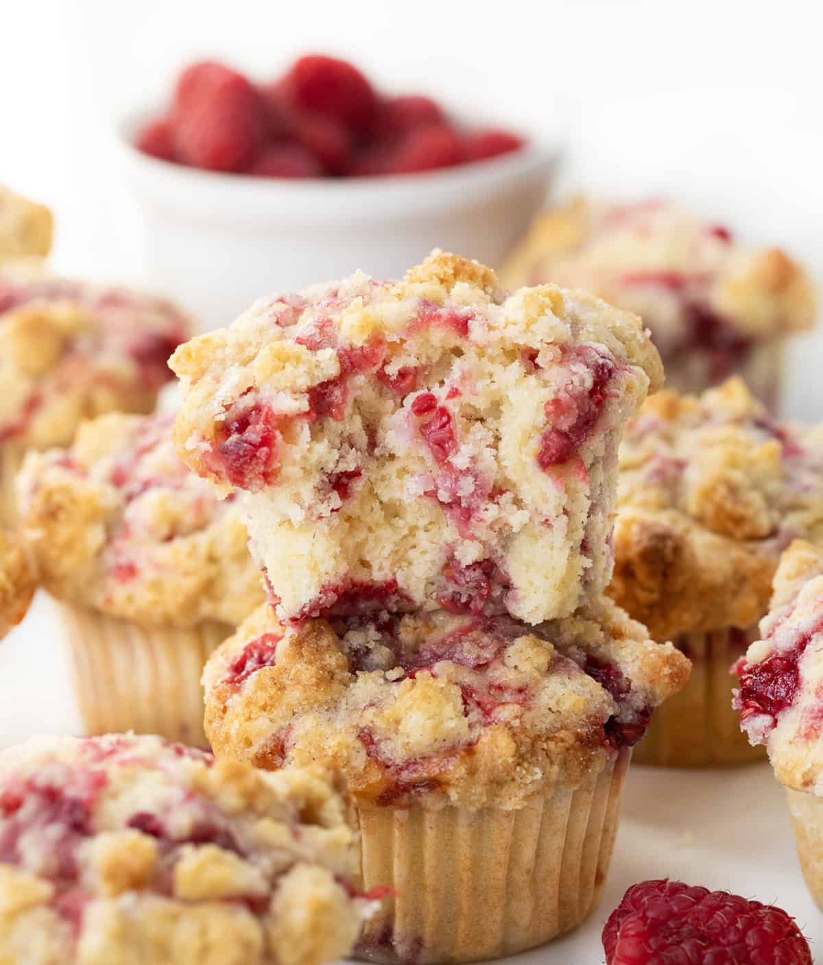 Stacked Double Raspberry Muffins with the top muffin halved showing the texture inside.