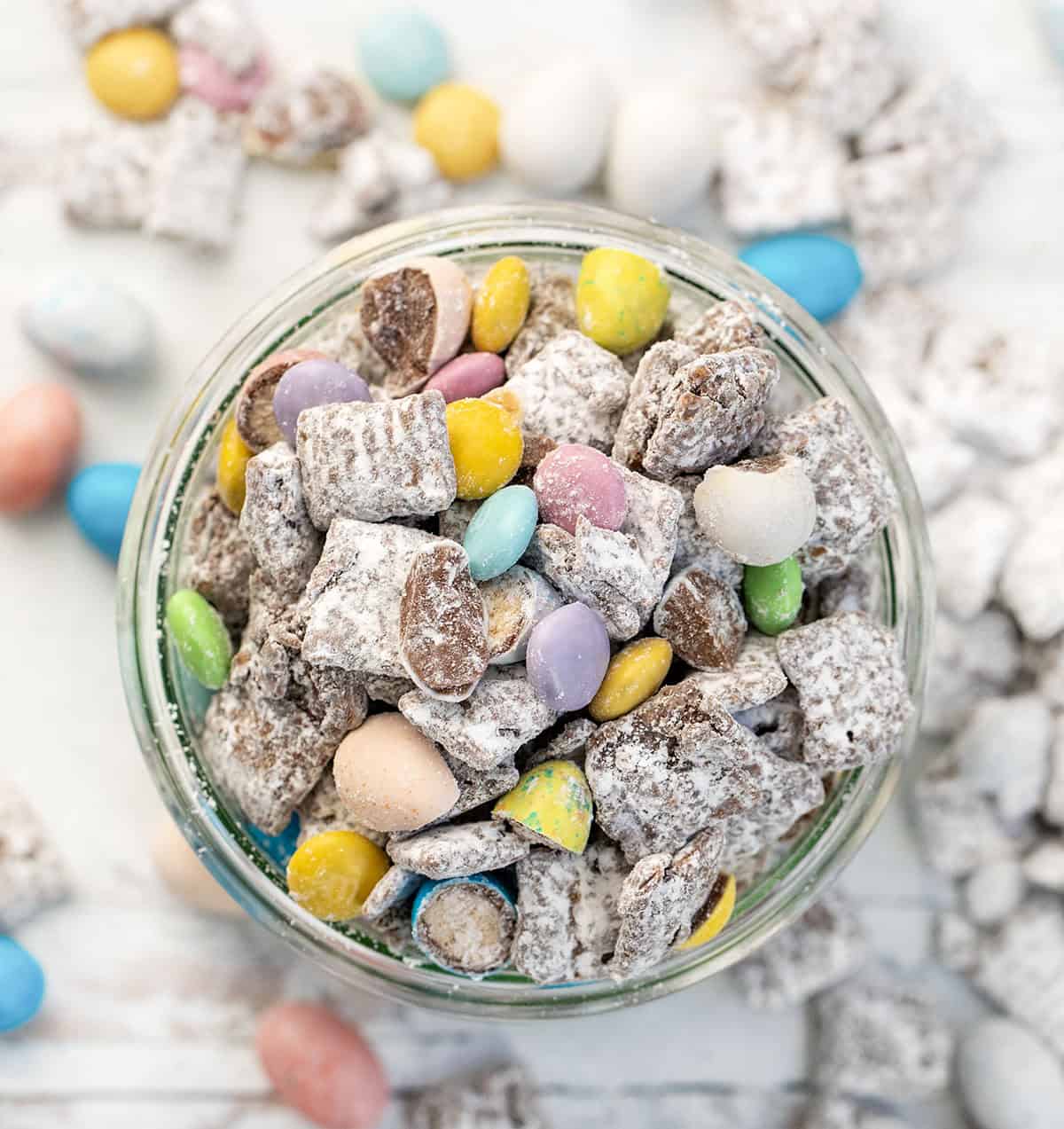 Looking down on a jar of Easter Puppy Chow on a white table.