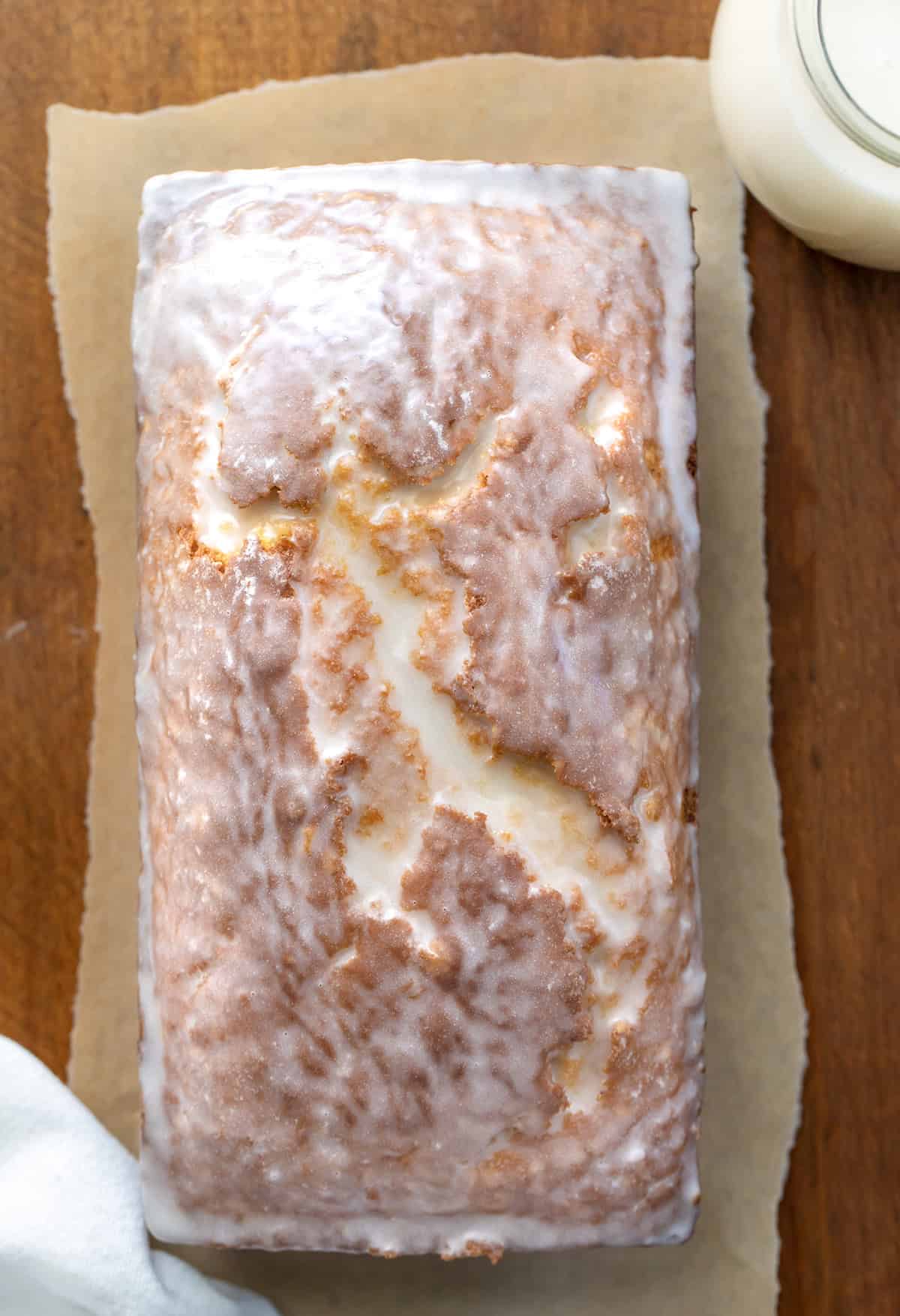 Looking down on a loaf of Glazed Donut Bread on a wooden table.