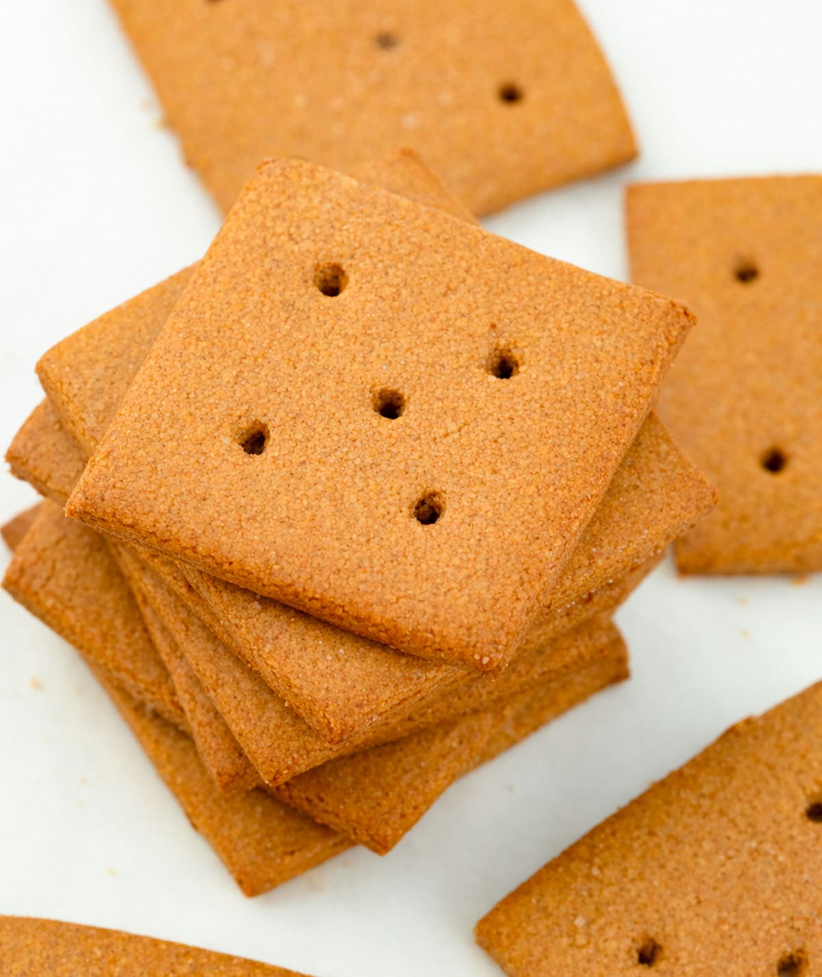 These Homemade Graham Crackers are crisp, slightly sweet, and full of warm cinnamon flavor! Looking down on a stack of Homemade Graham Crackers on a white table.