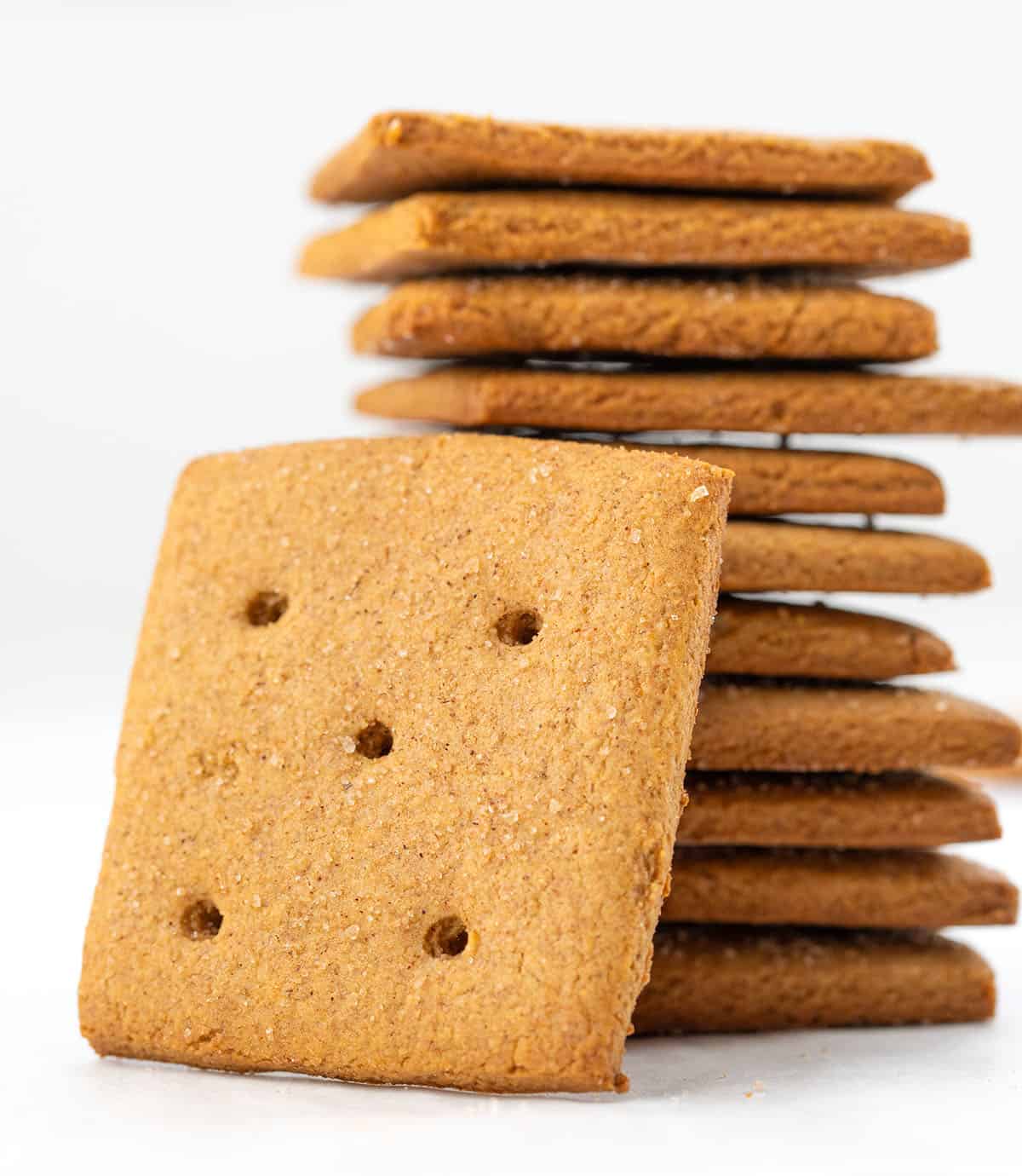 These Homemade Graham Crackers are crisp, slightly sweet, and full of warm cinnamon flavor! Stack of Homemade Graham Crackers on a white table.