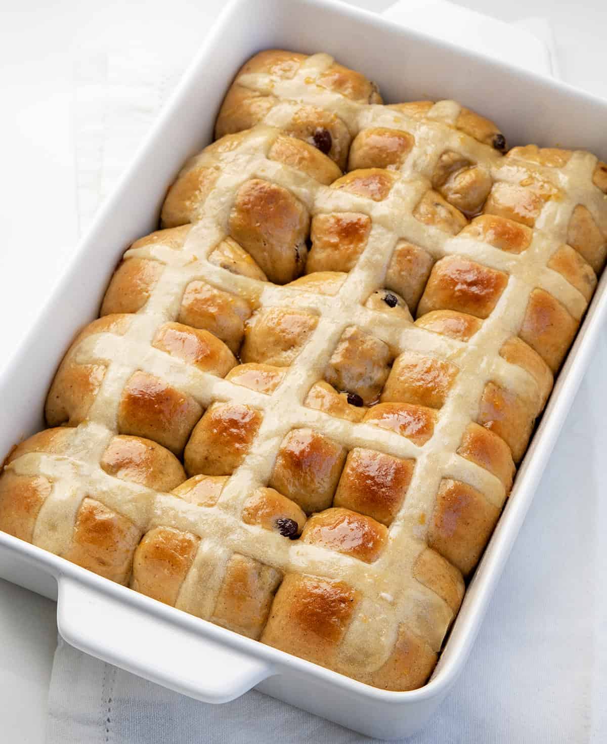 Close up of Hot Cross Buns in a white pan.