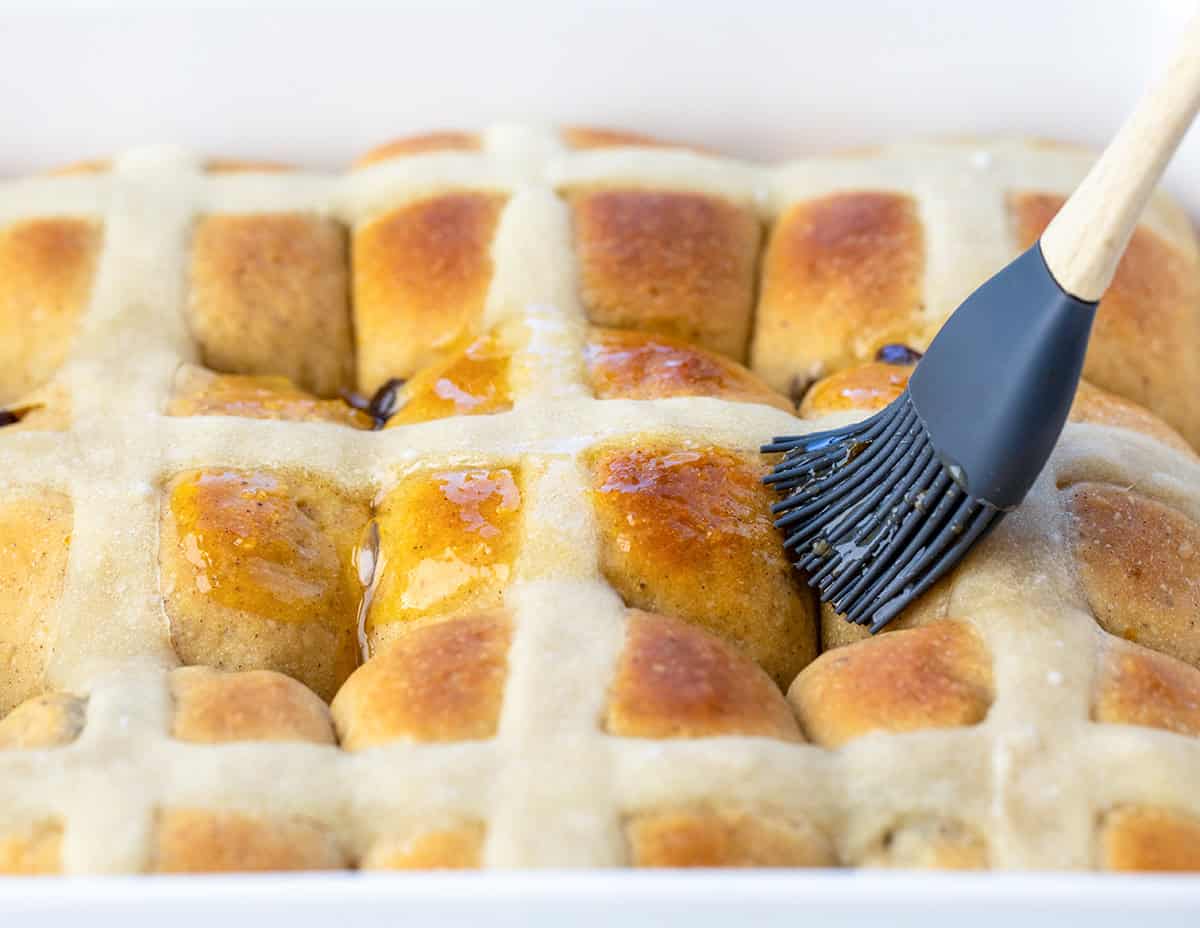 Brushing glaze over Hot Cross Buns.