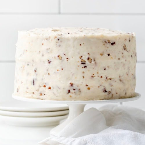 Italian Cream Cake on a white cake stand on a white counter.