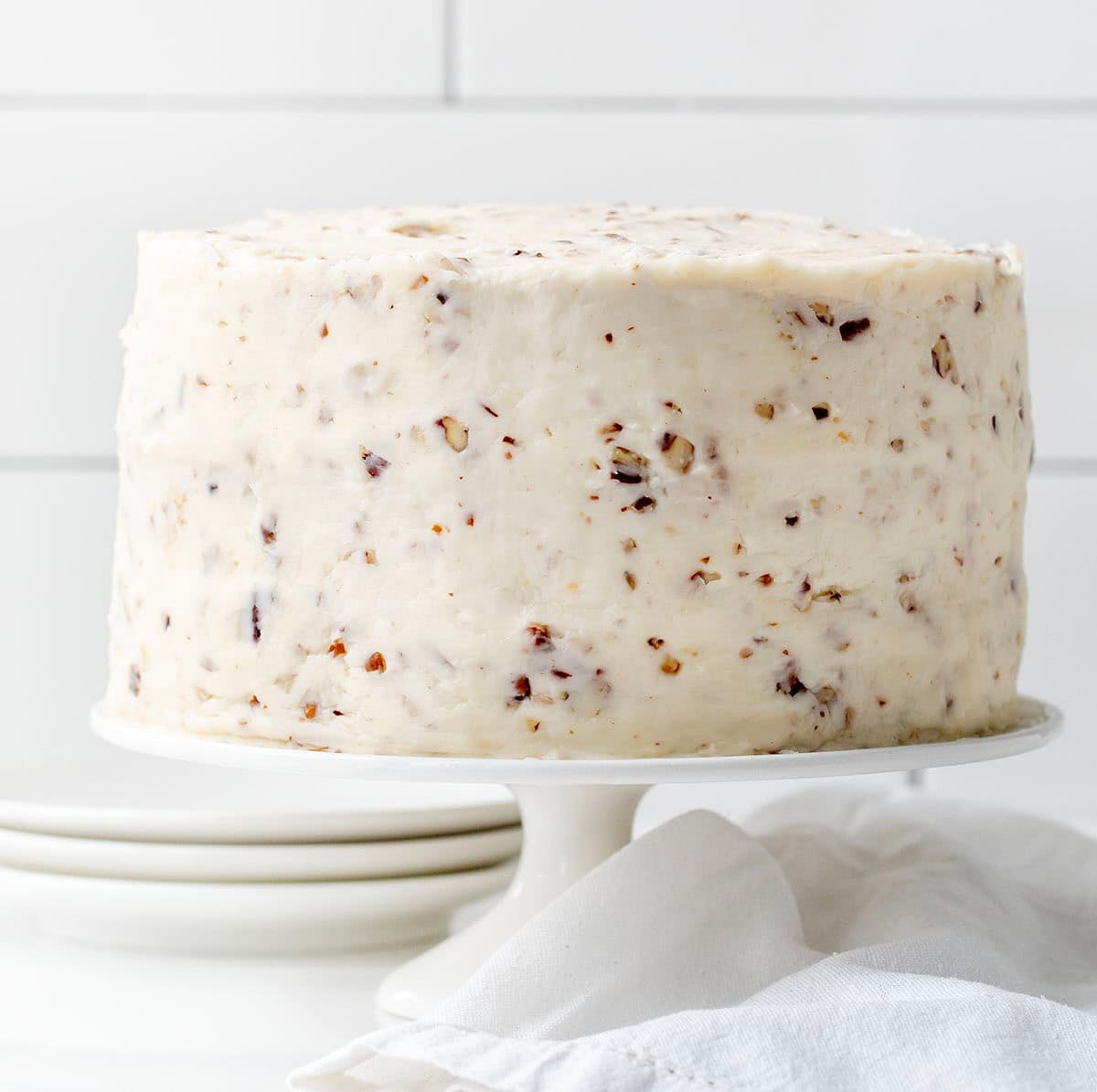 Italian Cream Cake on a white cake stand on a white counter.