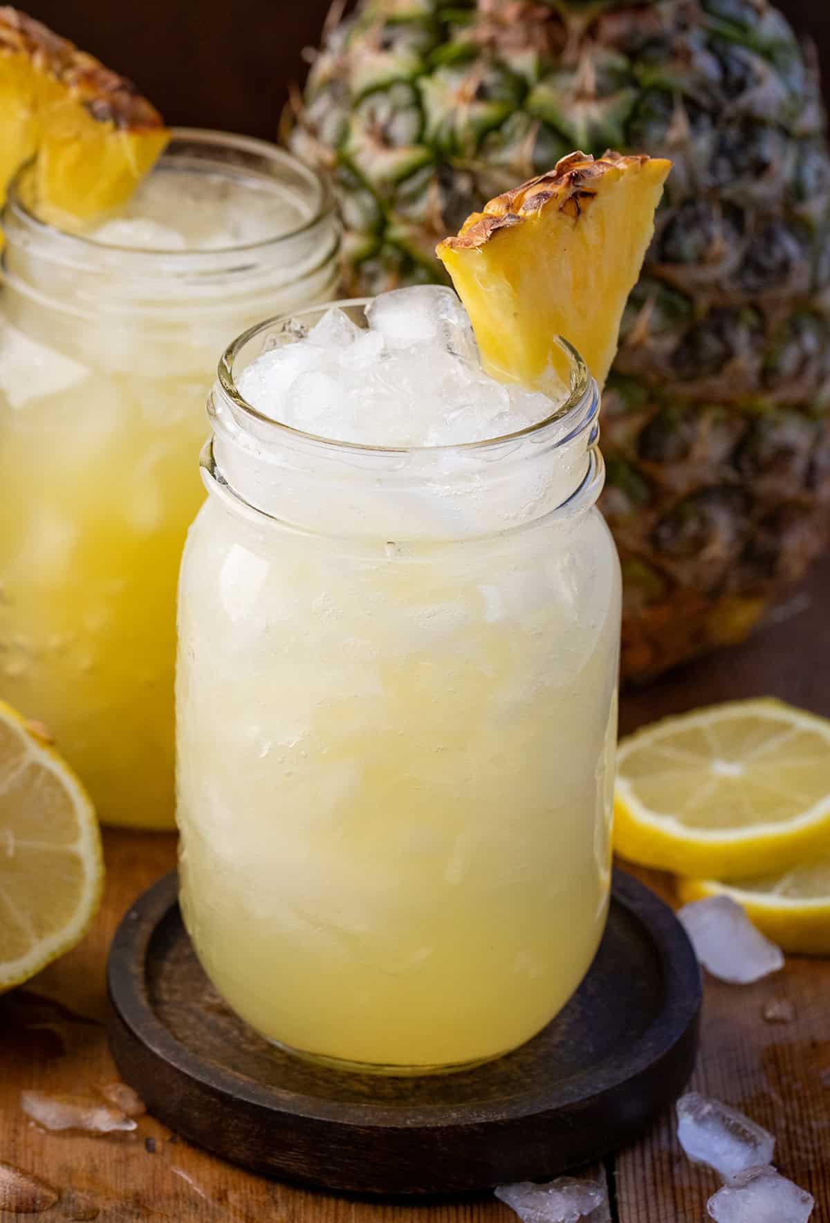 Mason jar of Pineapple Lemonade Punch with a fresh pineapple in the background.