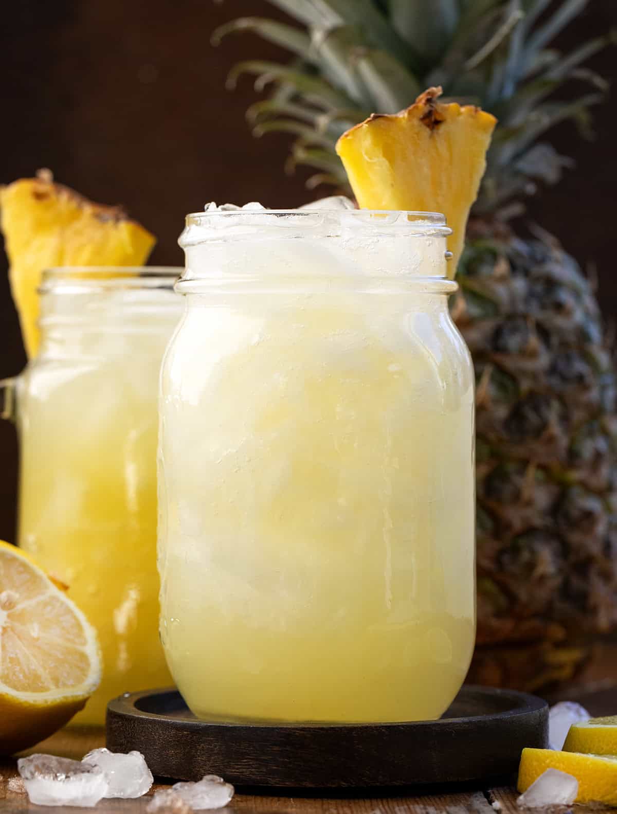 Mason jar of Pineapple Lemonade Punch with a fresh pineapple in the background.