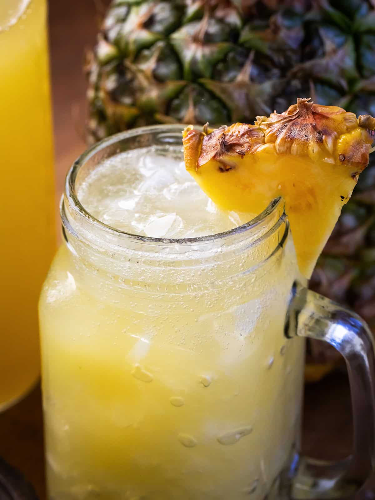 Close up of a Mason jar of Pineapple Lemonade Punch with a fresh pineapple in the background.