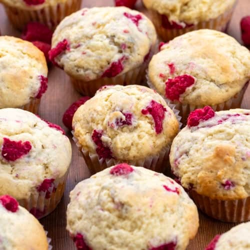 Close up of Raspberry Buttermilk Muffins on a wooden table.