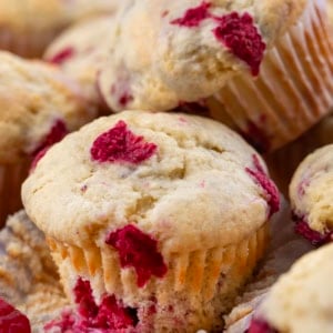 Partially unwrapped Raspberry Buttermilk Muffin next to other muffins.