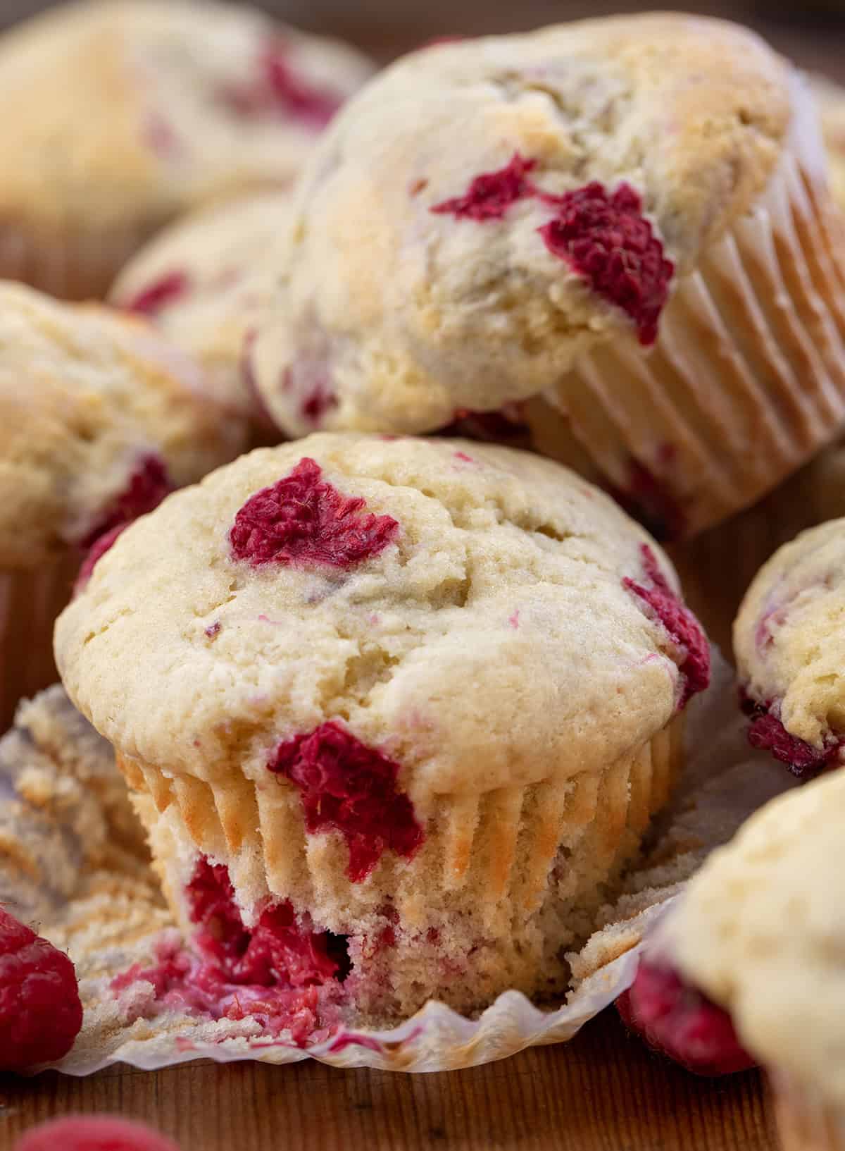 Partially unwrapped Raspberry Buttermilk Muffin next to other muffins.