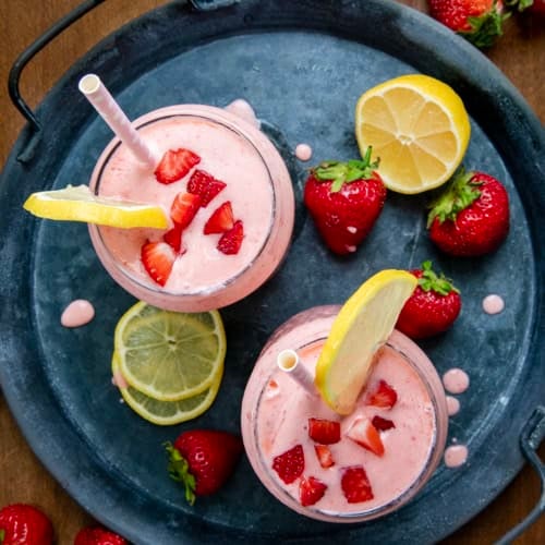 Looking down on a tray of Strawberry Lemonade Milkshakes with fresh lemon and fresh strawberry.