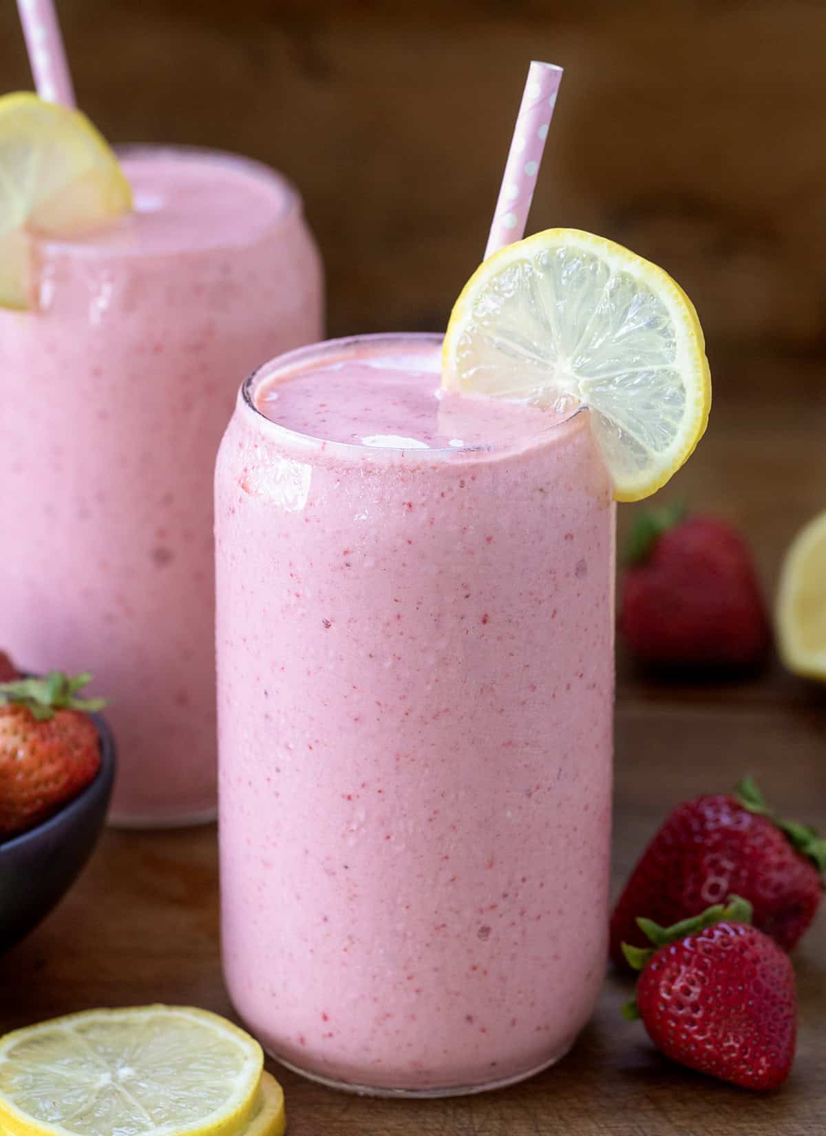Strawberry Lemonade Milkshake on a wooden table with fresh lemon and fresh strawberry.