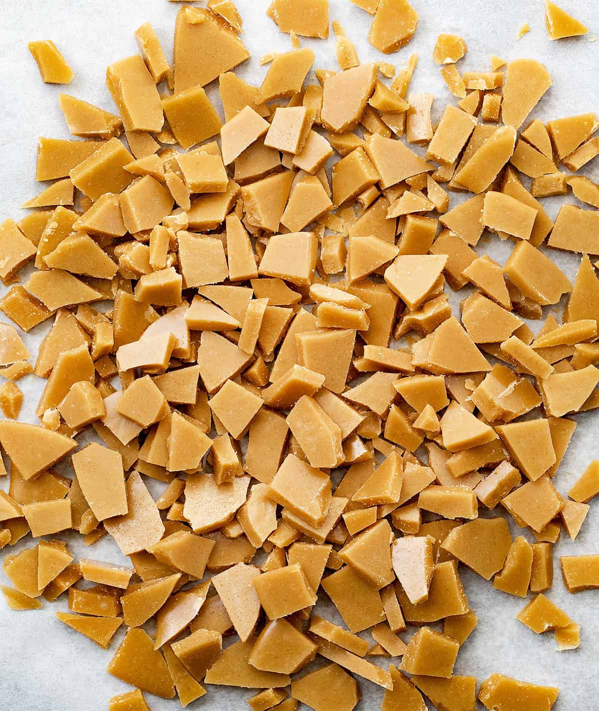 Toffee Bits laid out on a sheet tray covered with white parchment paper from overhead.