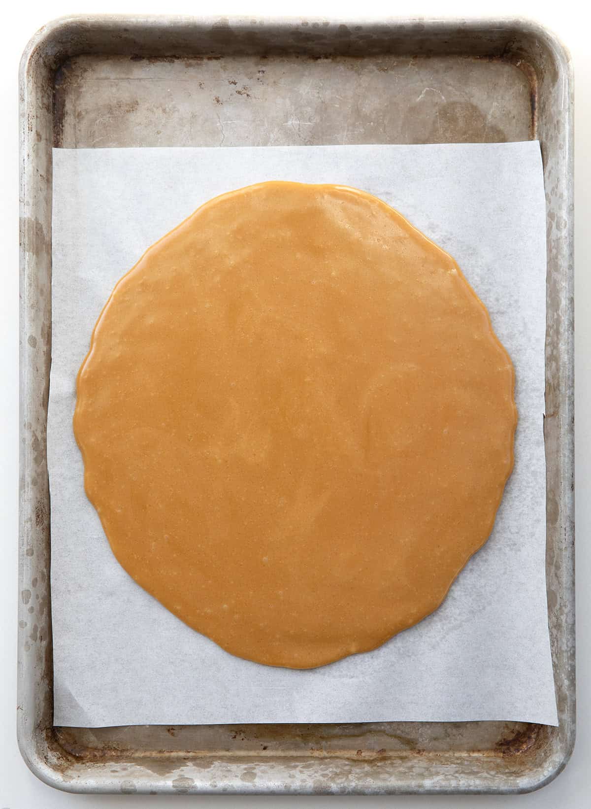 Toffee on a piece of white parchment paper on a sheet pan from overhead.