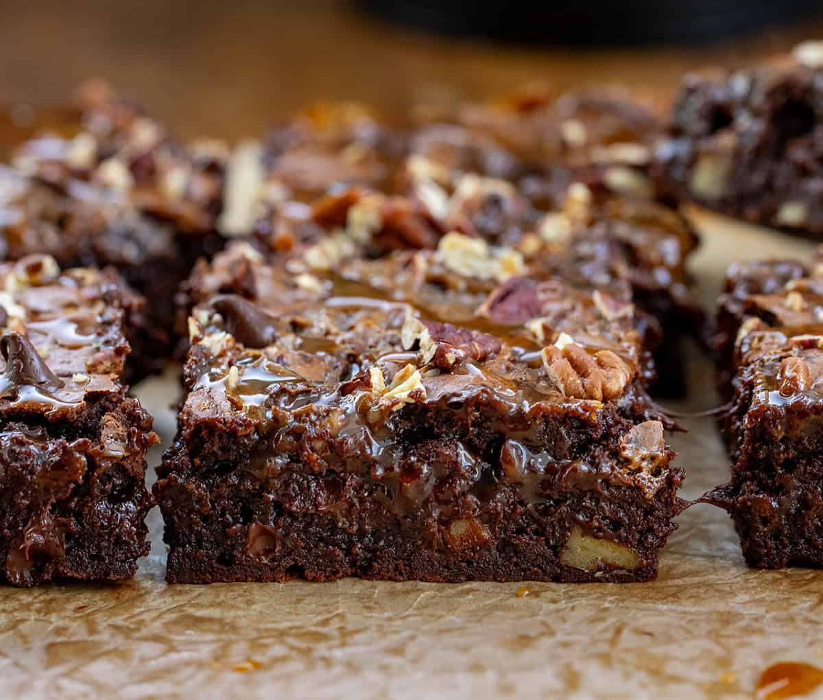 Close up of Turtle Brownies cut into squares on parchment paper.