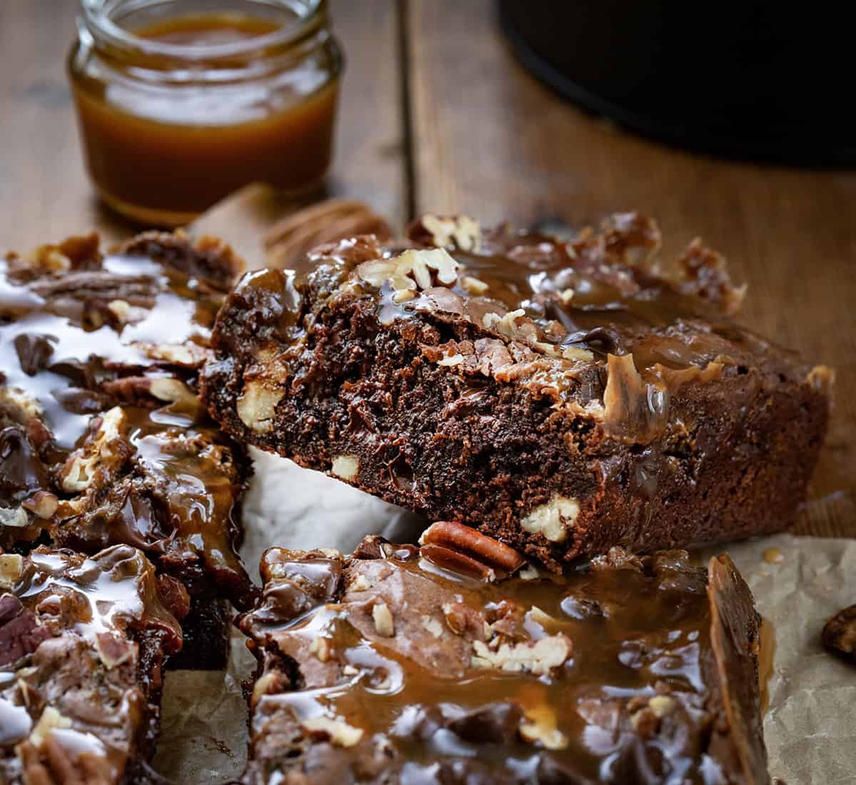 One Turtle Brownie resting on other brownies on a wooden table.