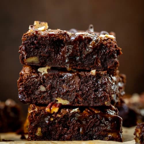 Stack of Turtle Brownies on a dark wooden table.