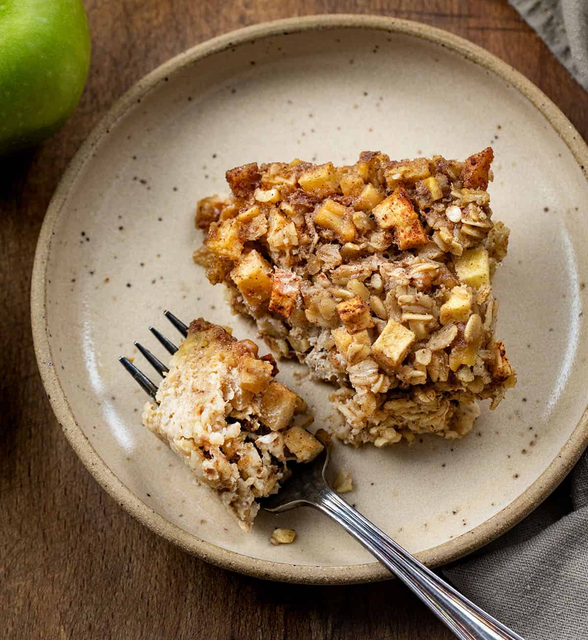 Apple Cinnamon Baked Oatmeal on a plate with a portion on a fork resting next to the piece.