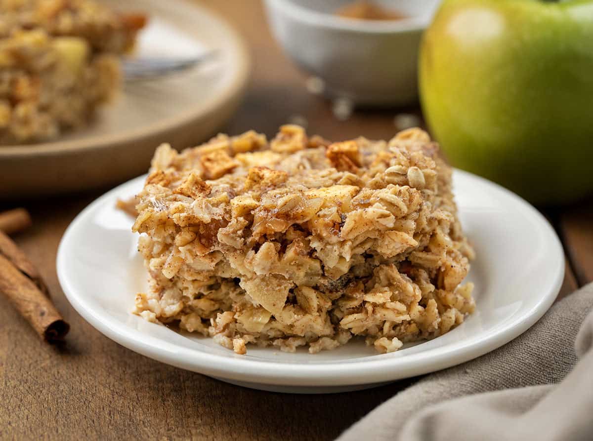 Piece of Apple Cinnamon Baked Oatmeal on a white plate on a wooden table.