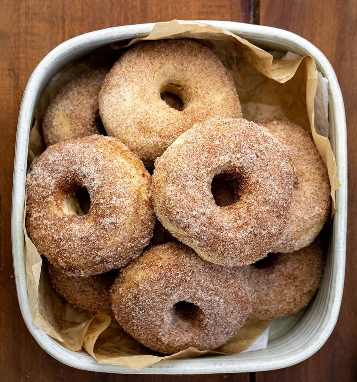 Container of Baked Donuts on a wooden table.