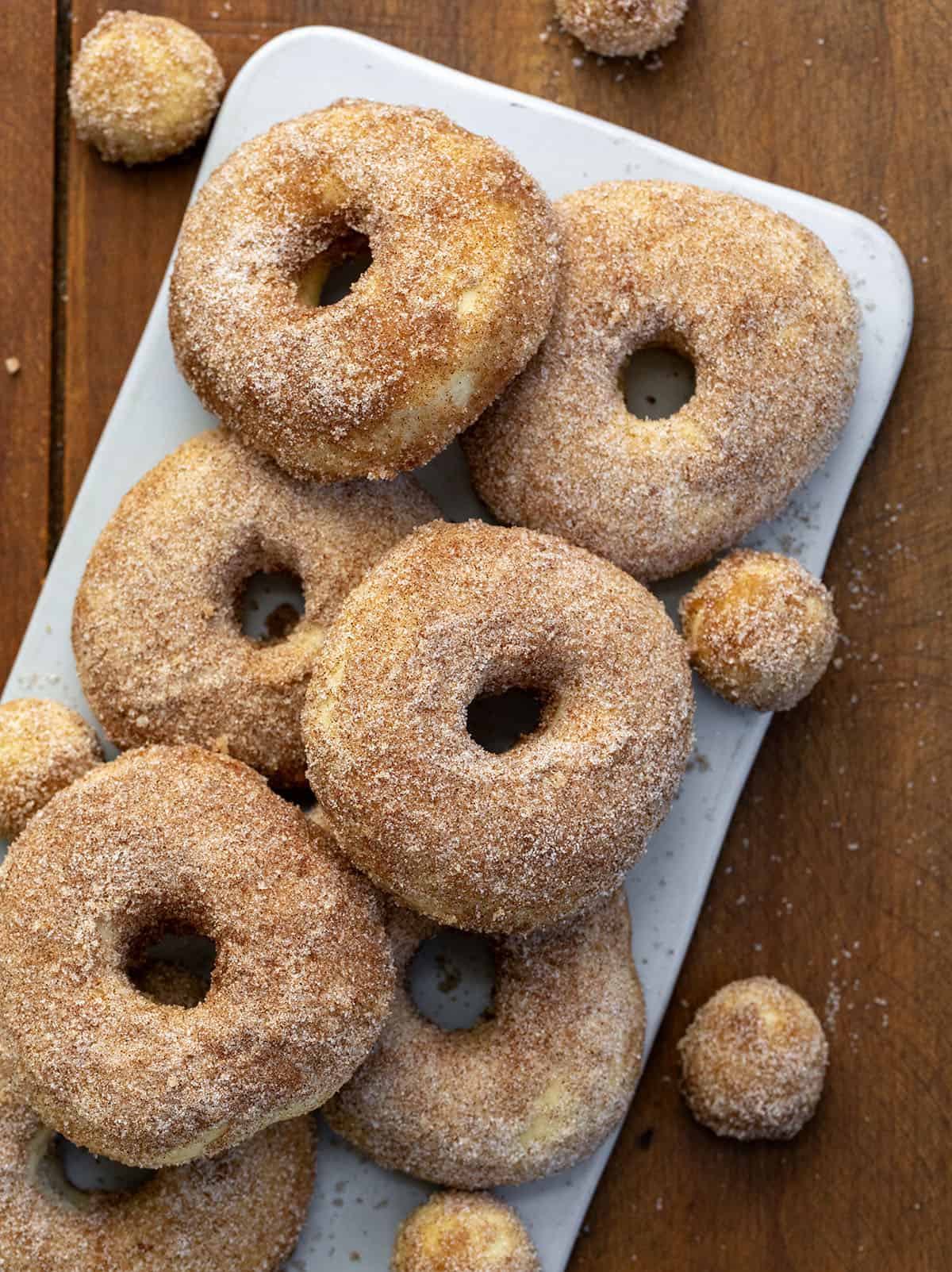 Cinnamon Sugar covered Baked Donuts and Donut Holes on a platter on a wooden table from overhead.