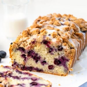 Cut into loaf of Blueberry Crumble Bread with a piece laying flat in front of it.