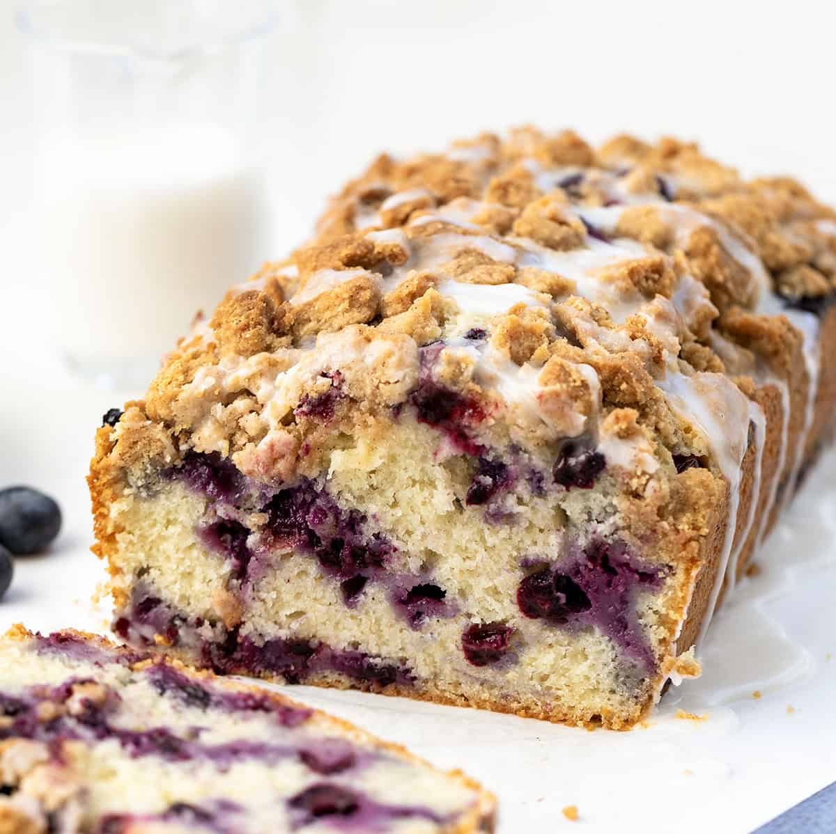 Cut into loaf of Blueberry Crumble Bread with a piece laying flat in front of it.
