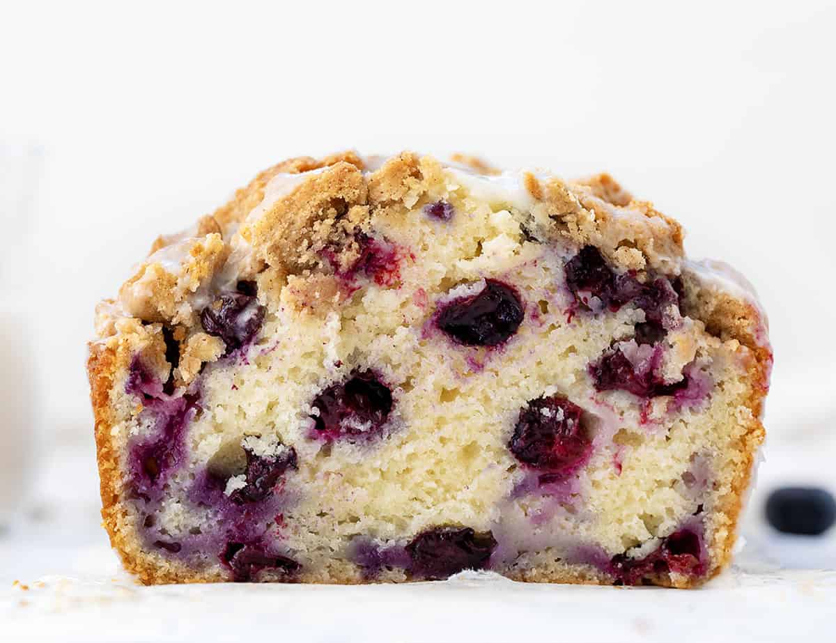 Close up of a cut into loaf of Blueberry Crumble Bread showing the tender crumb and blueberries.